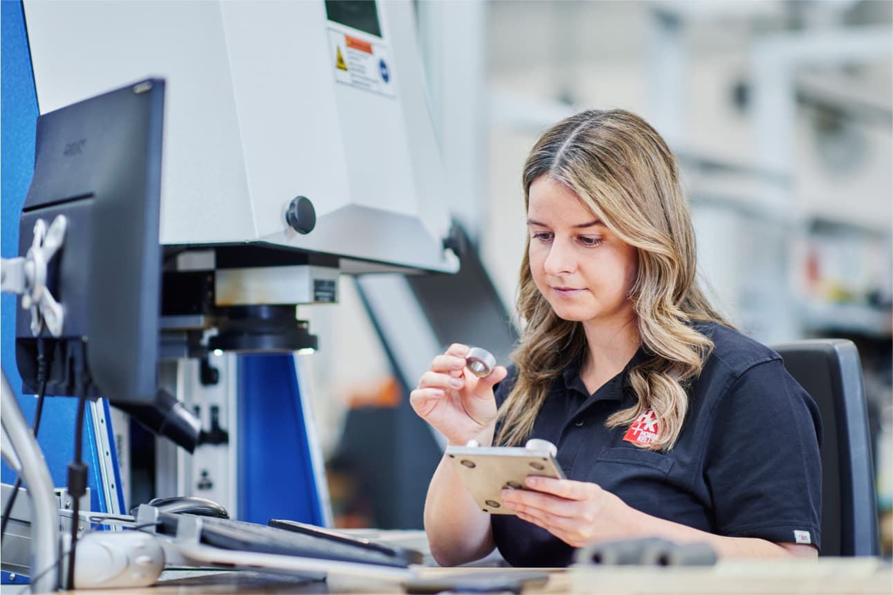 Hommel+Keller Mitarbeiterin inspiziert ein Bauteil zur Qualitätskontrolle im Bereich Rändeltechnik und Präzisionswerkzeuge